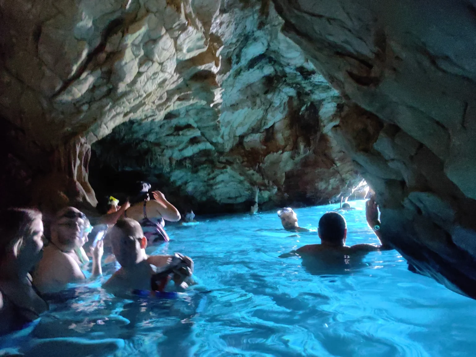 Swimmers inside Little Blue Cave on Hvar looking toward the entrance